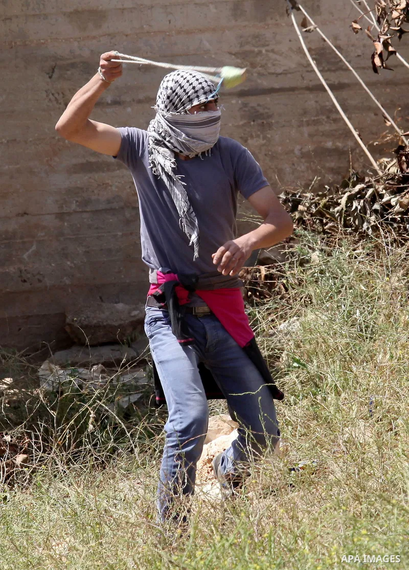 A Palestinian protester uses a slingshot to hurl stones towards Israeli security forces during clashes following a weekly demonstration against the expropriation of Palestinian land by Israel in the village of Kfar Qaddu...