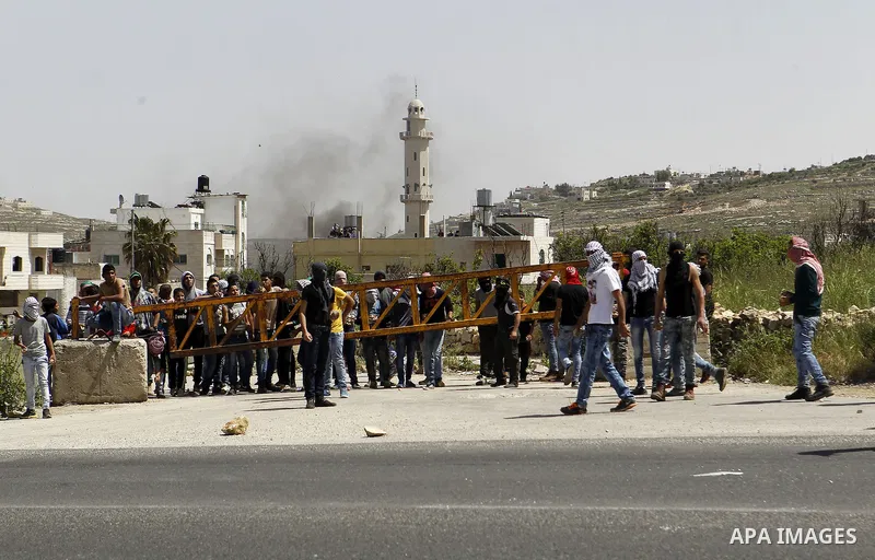 Palestinian protesters hurl stones towards Israeli troops during clashes in Arroub refugee camp north of the West Bank city of Hebron April 16, 2016. Photo by Wisam Hashlamoun