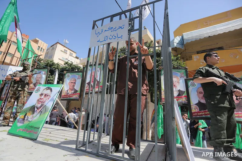 Members of the Ezzedine al-Qassam Brigades, the military wing of the Palestinian Islamist movement Hamas, stand next to mock jails during a rally marking Palestinian Prisoner Day in Gaza City on April 17, 2016. Photo by...