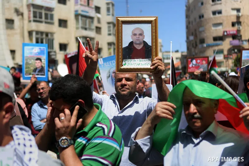 Palestinians hold pictures of Palestinians detained in Israeli prisons during a demonstration to mark Palestinian Prisoner Day in the West Bank city of Ramallah on April 17, 2016. Photo by Shadi Hatem