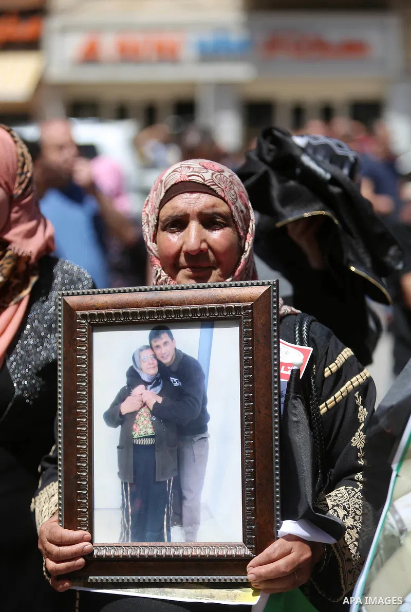 Palestinians hold pictures of Palestinians detained in Israeli prisons during a demonstration to mark Palestinian Prisoner Day in the West Bank city of Ramallah on April 17, 2016. Photo by Shadi Hatem