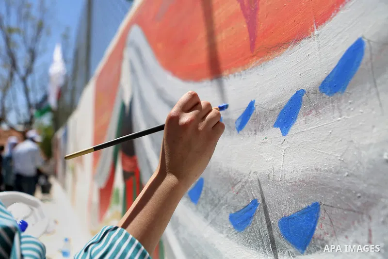 A Palestinian artist paints graffiti at school to mark Palestinian Prisoner Day in the West Bank city of Ramallah on April 17, 2016. Photo by Shadi Hatem
