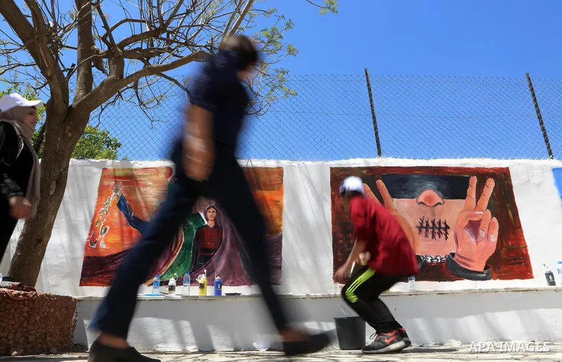 A Palestinian artist paints graffiti at school to mark Palestinian Prisoner Day in the West Bank city of Ramallah on April 17, 2016. Photo by Shadi Hatem
