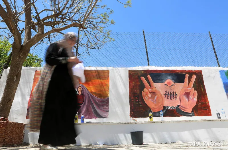 A Palestinian artist paints graffiti at school to mark Palestinian Prisoner Day in the West Bank city of Ramallah on April 17, 2016. Photo by Shadi Hatem