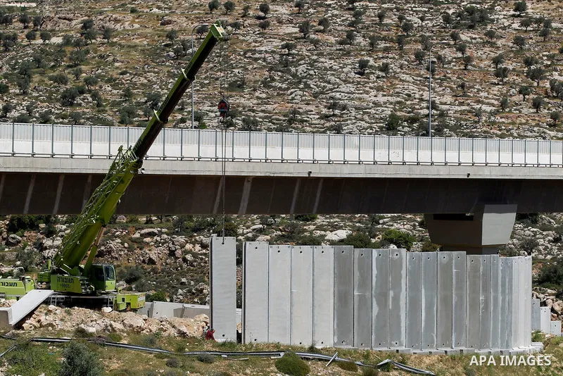 Israeli workers place a new section of Israel's separation concrete barrier in the Cremisan Valley, adjacent to the Christian Palestinian town of Beit Jala on April 17, 2016. The original route of the barrier was slated...