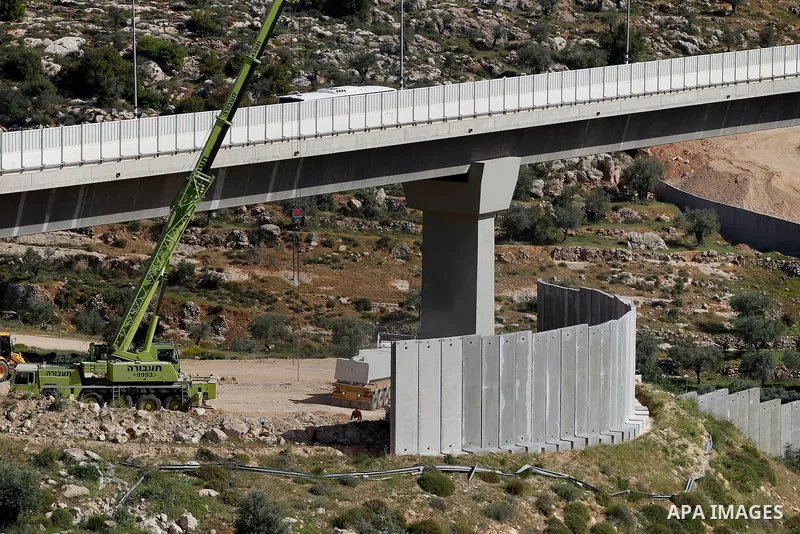 Israeli workers place a new section of Israel's separation concrete barrier in the Cremisan Valley, adjacent to the Christian Palestinian town of Beit Jala on April 17, 2016. The original route of the barrier was slated...