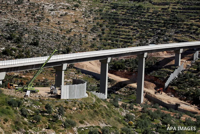 Israeli workers place a new section of Israel's separation concrete barrier in the Cremisan Valley, adjacent to the Christian Palestinian town of Beit Jala on April 17, 2016. The original route of the barrier was slated...
