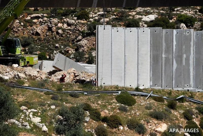 Israeli workers place a new section of Israel's separation concrete barrier in the Cremisan Valley, adjacent to the Christian Palestinian town of Beit Jala on April 17, 2016. The original route of the barrier was slated...