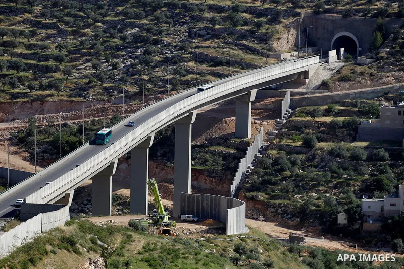 Israeli workers place a new section of Israel's separation concrete barrier in the Cremisan Valley, adjacent to the Christian Palestinian town of Beit Jala on April 17, 2016. The original route of the barrier was slated...