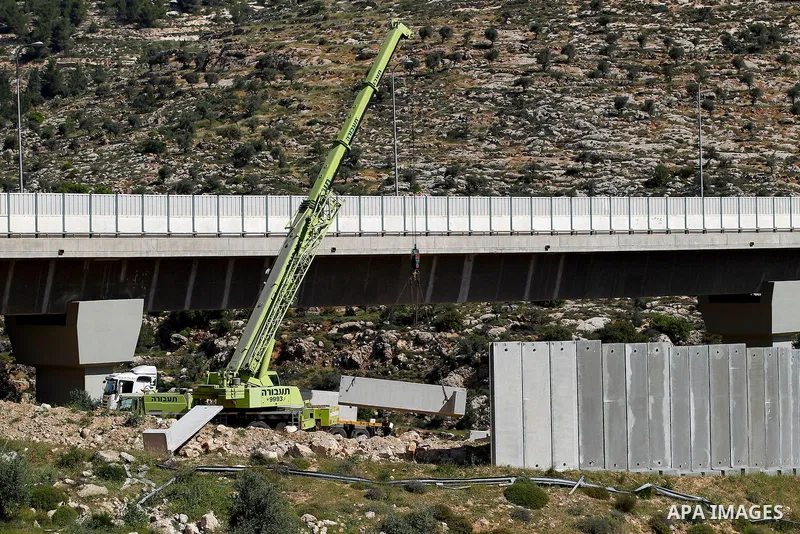 Israeli workers place a new section of Israel's separation concrete barrier in the Cremisan Valley, adjacent to the Christian Palestinian town of Beit Jala on April 17, 2016. The original route of the barrier was slated...