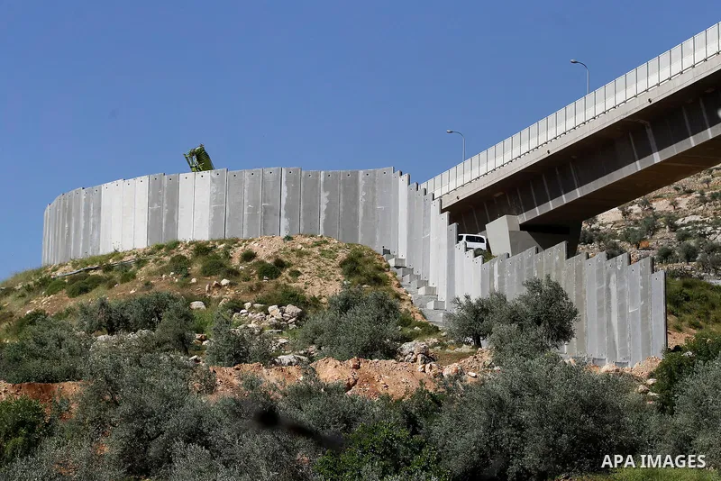 Israeli workers place a new section of Israel's separation concrete barrier in the Cremisan Valley, adjacent to the Christian Palestinian town of Beit Jala on April 17, 2016. The original route of the barrier was slated...