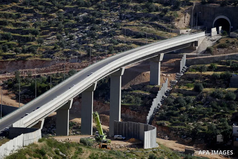 Israeli workers place a new section of Israel's separation concrete barrier in the Cremisan Valley, adjacent to the Christian Palestinian town of Beit Jala on April 17, 2016. The original route of the barrier was slated...