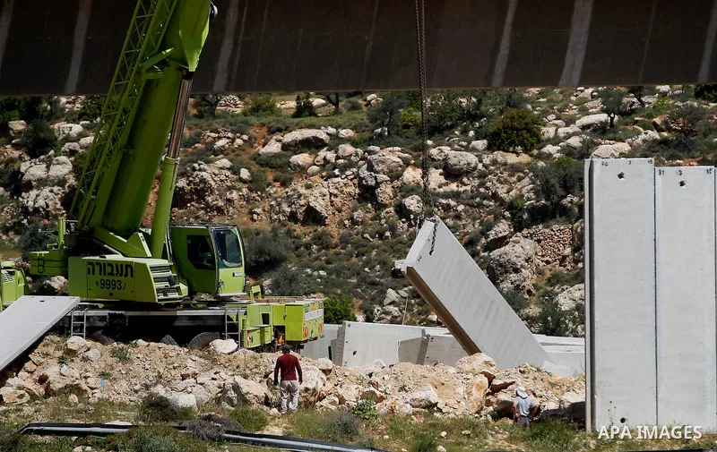 Israeli workers place a new section of Israel's separation concrete barrier in the Cremisan Valley, adjacent to the Christian Palestinian town of Beit Jala on April 17, 2016. The original route of the barrier was slated...