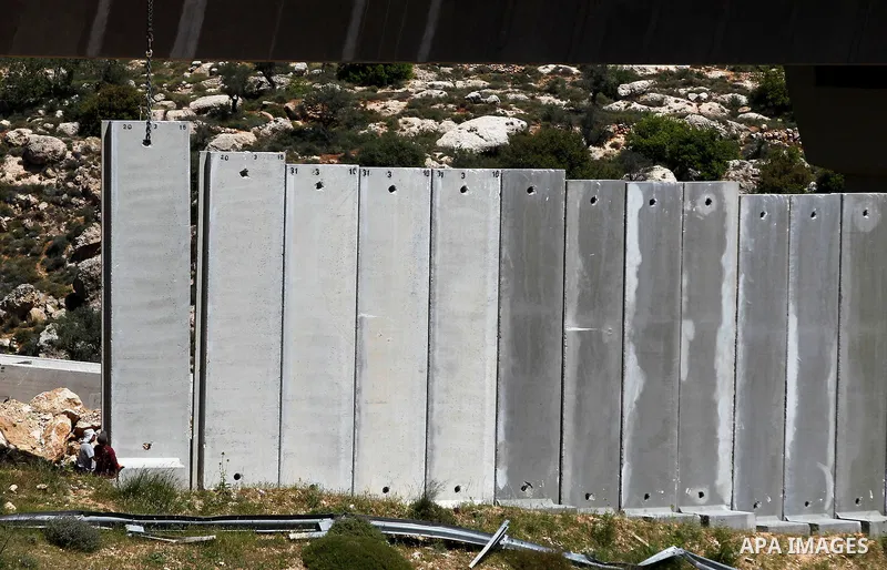 Israeli workers place a new section of Israel's separation concrete barrier in the Cremisan Valley, adjacent to the Christian Palestinian town of Beit Jala on April 17, 2016. The original route of the barrier was slated...