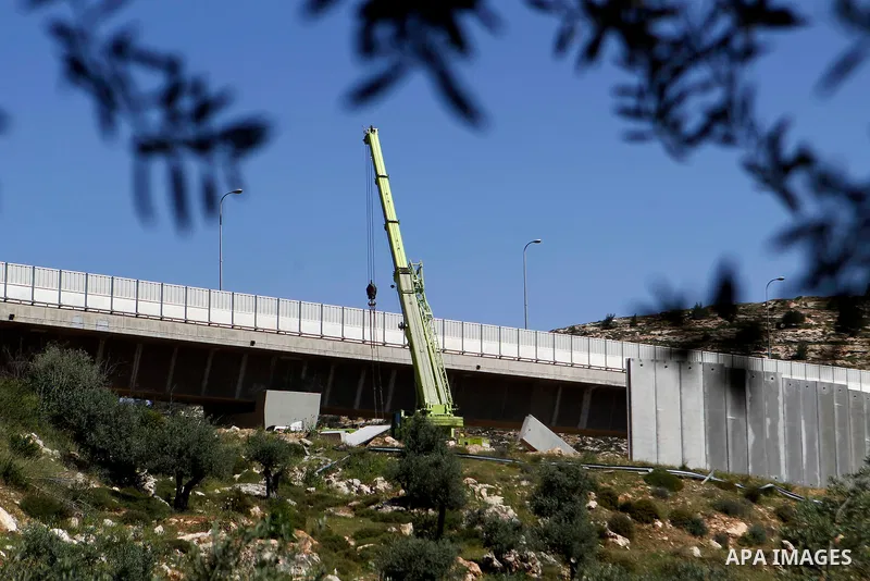 Israeli workers place a new section of Israel's separation concrete barrier in the Cremisan Valley, adjacent to the Christian Palestinian town of Beit Jala on April 17, 2016. The original route of the barrier was slated...