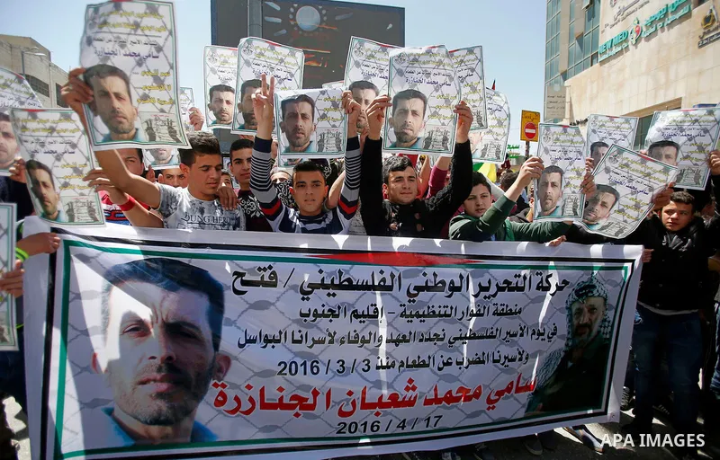 Palestinians hold pictures of Palestinians detained in Israeli prisons during a demonstration to mark Palestinian Prisoner Day in the West Bank city of Hebron on April 17, 2016. Photo by Wisam Hashlamoun