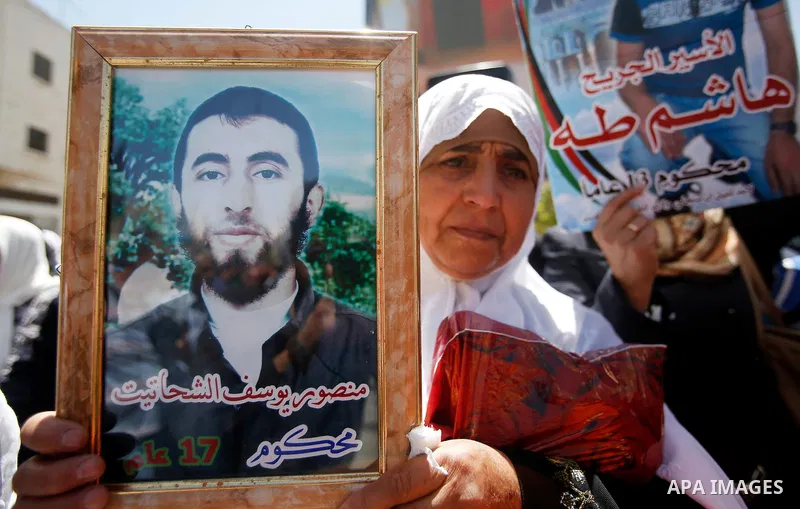 Palestinians hold pictures of Palestinians detained in Israeli prisons during a demonstration to mark Palestinian Prisoner Day in the West Bank city of Hebron on April 17, 2016. Photo by Wisam Hashlamoun
