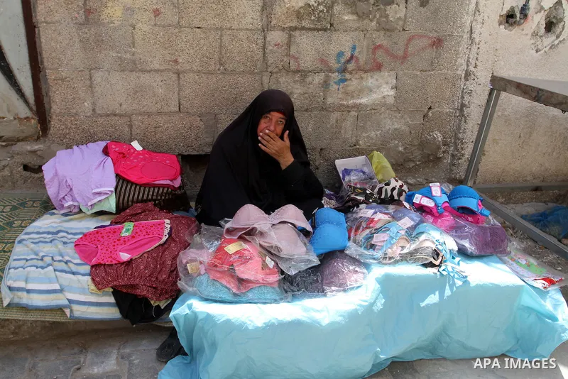 A Palestinian woman sells clothes at a market in Rafah in the southern Gaza Strip, April 19, 2016. Photo by Abed Rahim Khatib