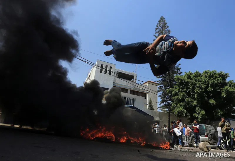 Palestinian owners of houses which were destroyed during the recent Israeli war, burn tires during a protest, in front of high commissioner for human rights headquarters, in Gaza City on April 20, 2016. Israeli occupatio...