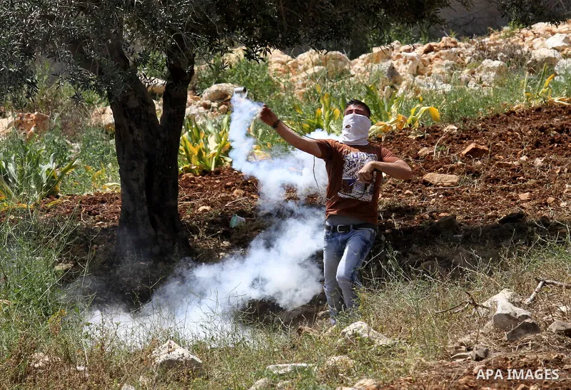A Palestinian protester throws back a tear gas canister fired by Israeli security forces during clashes following a weekly demonstration against the expropriation of Palestinian land by Israel in the village of Kfar Qadd...