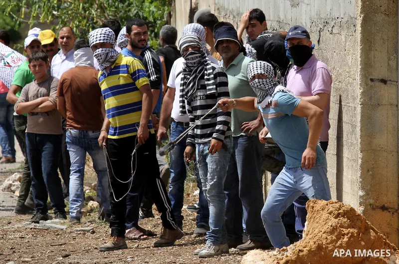 A Palestinian protester uses a slingshot to hurl stones towards Israeli security forces during clashes following a weekly demonstration against the expropriation of Palestinian land by Israel in the village of Kfar Qaddu...
