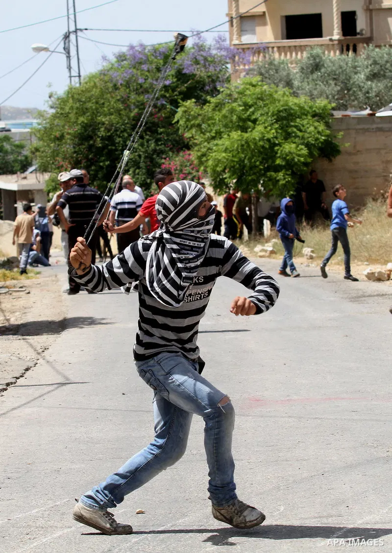 A Palestinian protester uses a slingshot to hurl stones towards Israeli security forces during clashes following a weekly demonstration against the expropriation of Palestinian land by Israel in the village of Kfar Qaddu...