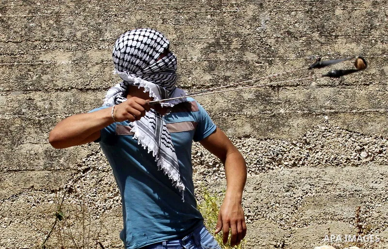 A Palestinian protester uses a slingshot to hurl stones towards Israeli security forces during clashes following a weekly demonstration against the expropriation of Palestinian land by Israel in the village of Kfar Qaddu...