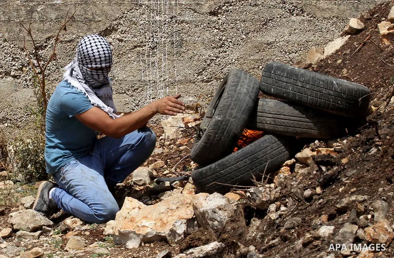 A Palestinian protester burns tires during clashes with Israeli security forces following a weekly demonstration against the expropriation of Palestinian land by Israel in the village of Kfar Qaddum, near Nablus, in the...