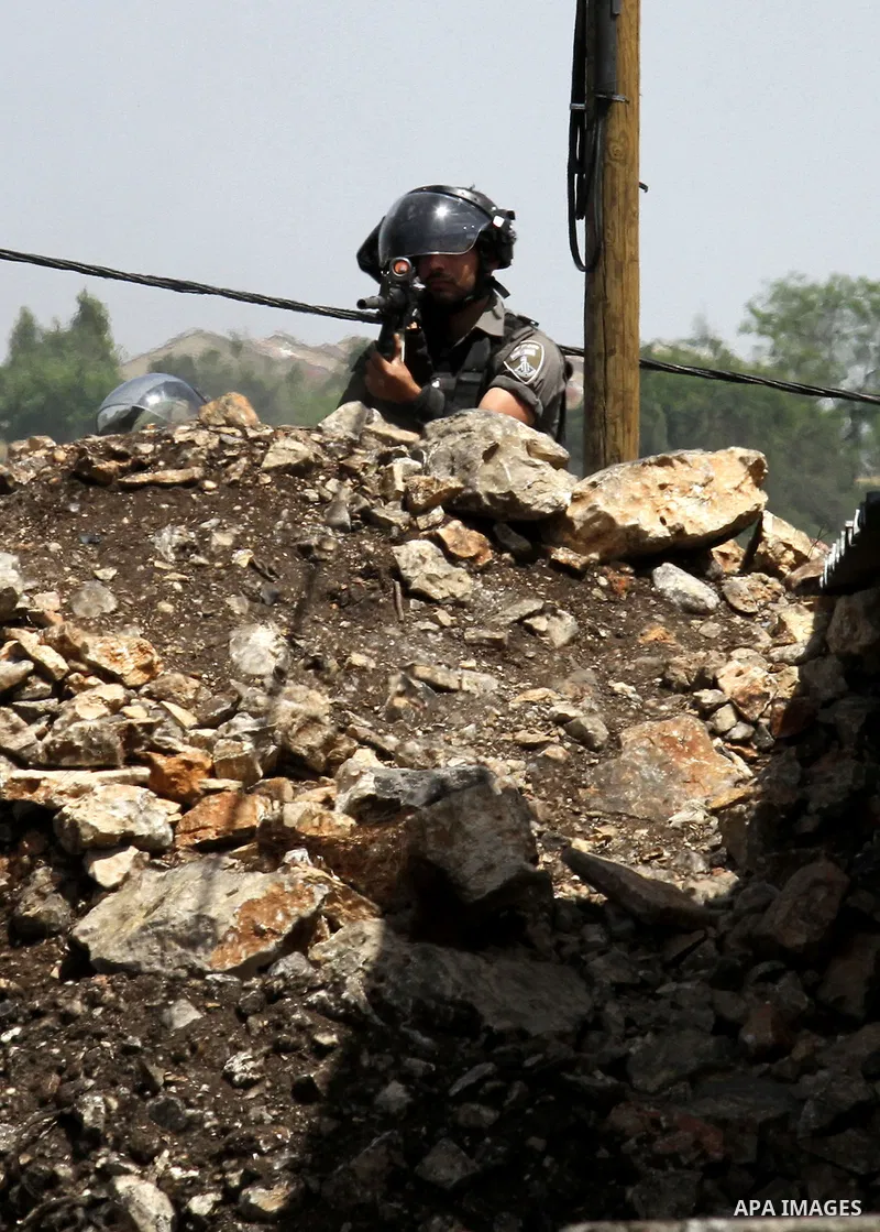 A member of Israeli security forces takes aim as he holds a position during clashes with Palestinian protesters following a weekly demonstration against the expropriation of Palestinian land by Israel in the village of K...