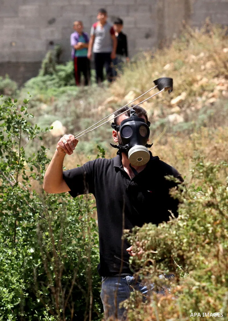 A Palestinian protester uses a slingshot to hurl stones towards Israeli security forces during clashes following a weekly demonstration against the expropriation of Palestinian land by Israel in the village of Kfar Qaddu...