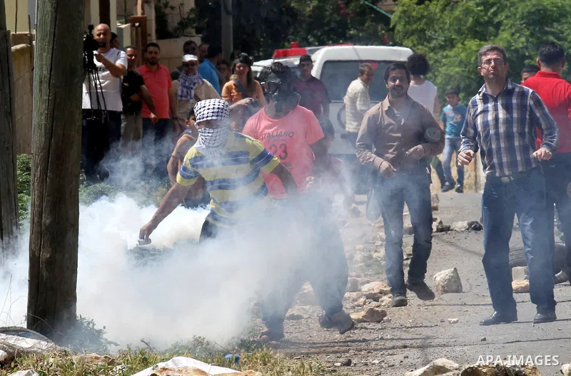 A Palestinian protester throws back a tear gas canister fired by Israeli security forces during clashes following a weekly demonstration against the expropriation of Palestinian land by Israel in the village of Kfar Qadd...