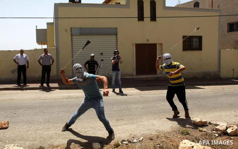 A Palestinian protester uses a slingshot to hurl stones towards Israeli security forces during clashes following a weekly demonstration against the expropriation of Palestinian land by Israel in the village of Kfar Qaddu...