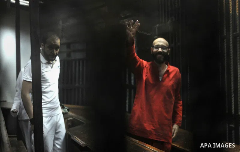 Ahmed Abdel-Aaty, the former head of Egypt's ousted Islamist president's office, wearing a red uniform, gestures from behind the bars during his trial at the police academy in Cairo on April 23, 2016. An Egyptian court p...