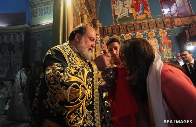Reverend Archbishop of Tiberias, Alexios, gives the eucharist during the Greek Orthodox Christian Palm Sunday mass at St.Porphyrios Church in Gaza City, on April 24, 2016. Palm Sunday marks the triumphant return of Jesus...