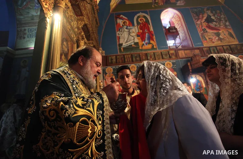 Reverend Archbishop of Tiberias, Alexios, gives the eucharist during the Greek Orthodox Christian Palm Sunday mass at St.Porphyrios Church in Gaza City, on April 24, 2016. Palm Sunday marks the triumphant return of Jesus...