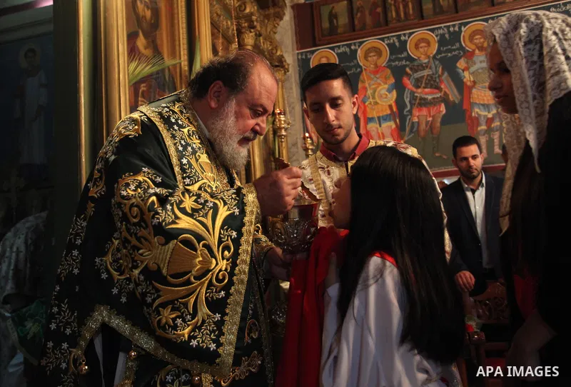 Reverend Archbishop of Tiberias, Alexios, gives the eucharist during the Greek Orthodox Christian Palm Sunday mass at St.Porphyrios Church in Gaza City, on April 24, 2016. Palm Sunday marks the triumphant return of Jesus...