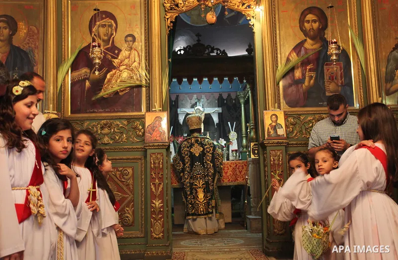 Reverend Archbishop of Tiberias, Alexios, gives the eucharist during the Greek Orthodox Christian Palm Sunday mass at St.Porphyrios Church in Gaza City, on April 24, 2016. Palm Sunday marks the triumphant return of Jesus...