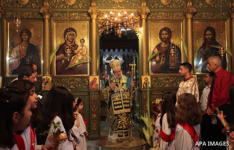 Reverend Archbishop of Tiberias, Alexios, gives the eucharist during the Greek Orthodox Christian Palm Sunday mass at St.Porphyrios Church in Gaza City, on April 24, 2016. Palm Sunday marks the triumphant return of Jesus...