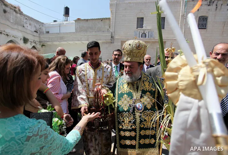 Reverend Archbishop of Tiberias, Alexios, gives the eucharist during the Greek Orthodox Christian Palm Sunday mass at St.Porphyrios Church in Gaza City, on April 24, 2016. Palm Sunday marks the triumphant return of Jesus...