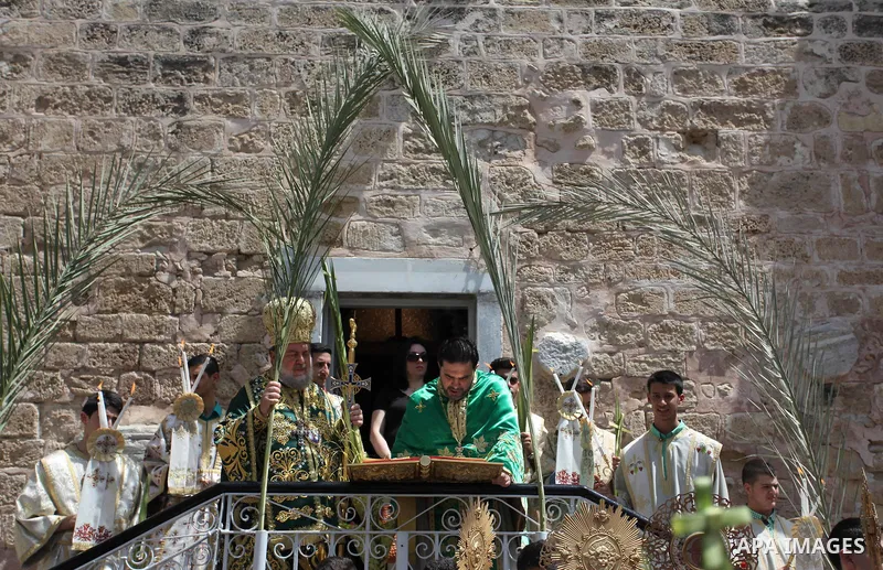 Reverend Archbishop of Tiberias, Alexios, gives the eucharist during the Greek Orthodox Christian Palm Sunday mass at St.Porphyrios Church in Gaza City, on April 24, 2016. Palm Sunday marks the triumphant return of Jesus...
