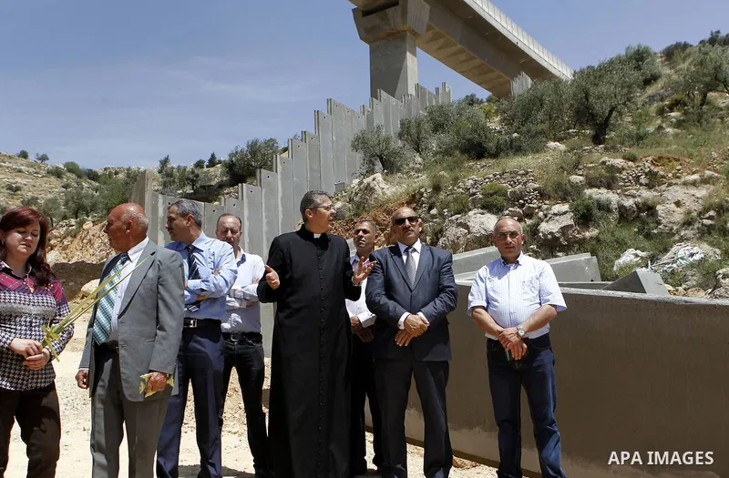 Palestinians hold a mass during a protest at the construction site of a section of the Israeli barrier in the West Bank city of Beit Jala, near Bethlehem April 24, 2016. Photo by Wisam Hashlamoun