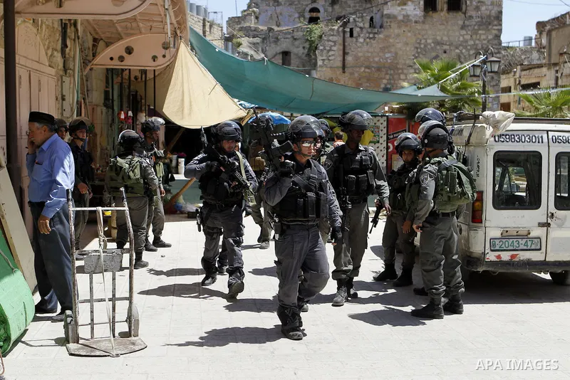 Israeli troops stand guard as Israeli settlers have a tour during the Jewish holiday of Passover in the West Bank city of Hebron, on April 25, 2016. Photo by Wisam Hashlamoun