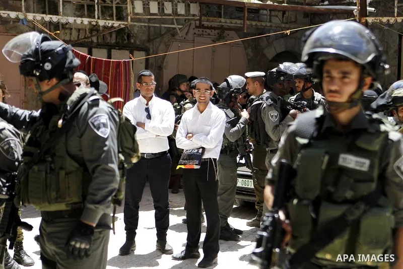 Israeli troops stand guard as Israeli settlers have a tour during the Jewish holiday of Passover in the West Bank city of Hebron, on April 25, 2016. Photo by Wisam Hashlamoun