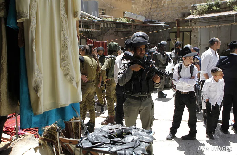Israeli troops stand guard as Israeli settlers have a tour during the Jewish holiday of Passover in the West Bank city of Hebron, on April 25, 2016. Photo by Wisam Hashlamoun