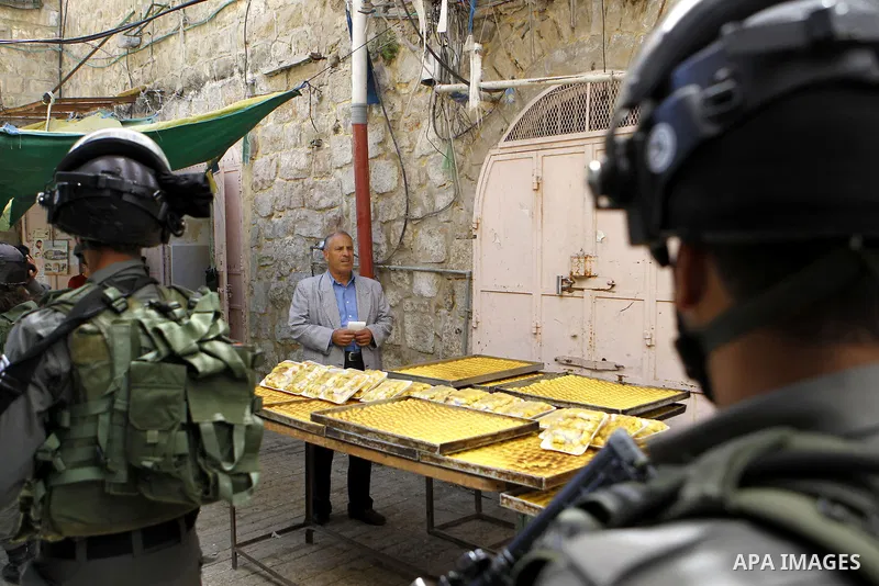 Israeli troops stand guard as Israeli settlers have a tour during the Jewish holiday of Passover in the West Bank city of Hebron, on April 25, 2016. Photo by Wisam Hashlamoun