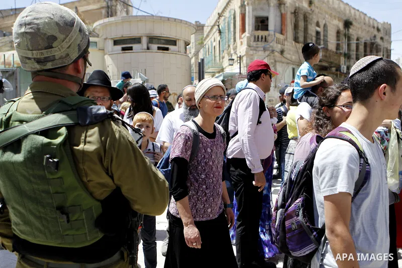 Israeli troops stand guard as Israeli settlers have a tour during the Jewish holiday of Passover in the West Bank city of Hebron, on April 25, 2016. Photo by Wisam Hashlamoun