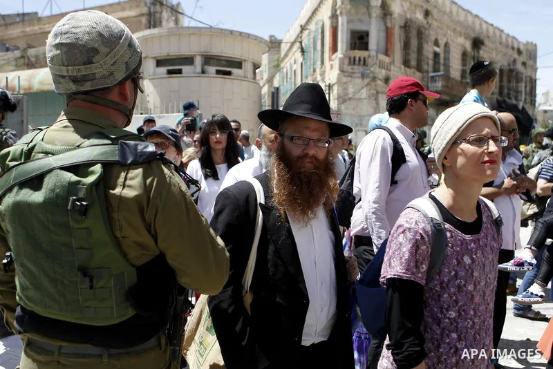 Israeli troops stand guard as Israeli settlers have a tour during the Jewish holiday of Passover in the West Bank city of Hebron, on April 25, 2016. Photo by Wisam Hashlamoun
