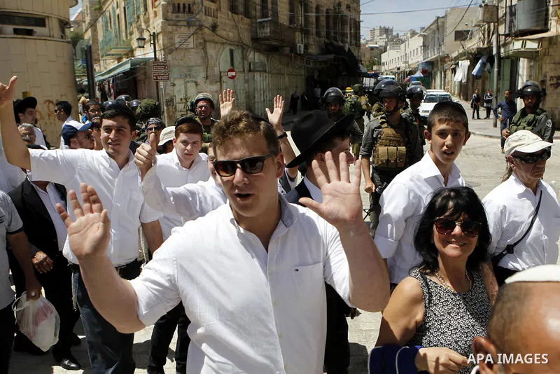Israeli troops stand guard as Israeli settlers have a tour during the Jewish holiday of Passover in the West Bank city of Hebron, on April 25, 2016. Photo by Wisam Hashlamoun