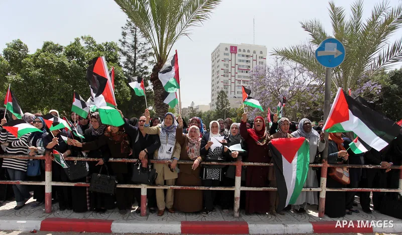 Palestinian women hold national flags during a demonstration to calling for an end in the political division and the national reconciliation in Gaza city, on April 26, 2016. Photo by Ashraf Amra
