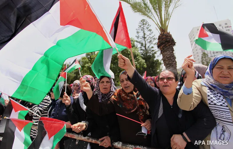 Palestinian women hold national flags during a demonstration to calling for an end in the political division and the national reconciliation in Gaza city, on April 26, 2016. Photo by Ashraf Amra